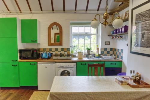 a kitchen with green cabinets and a sink at Bramble Cottage in Whiteparish