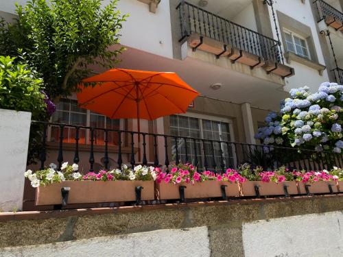 サンシェンショにあるApartamento Sanxenxo Playa Silgar 30mの花の咲くバルコニーのオレンジ傘