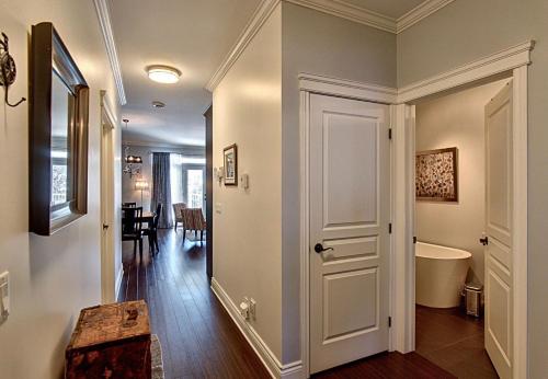 a hallway with a door leading to a bathroom with a tub at Le Champlain Condo-Hôtel in Bromont