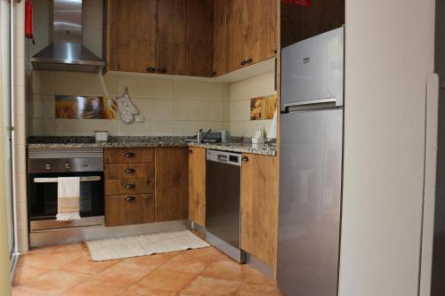 a kitchen with wooden cabinets and a stainless steel refrigerator at Home Sweet Home VRSA in Vila Real de Santo António