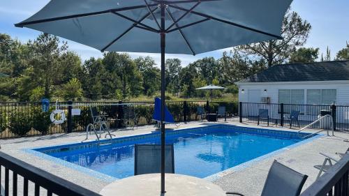 a pool with an umbrella and a table and chairs at Baymont by Wyndham Dublin in Dublin