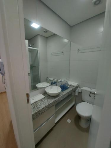 uma casa de banho com 2 lavatórios, um WC e um espelho. em Flat Completo em Cotia