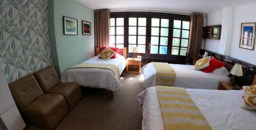 a hotel room with two beds and a chair at Hotel Churup in Huaraz