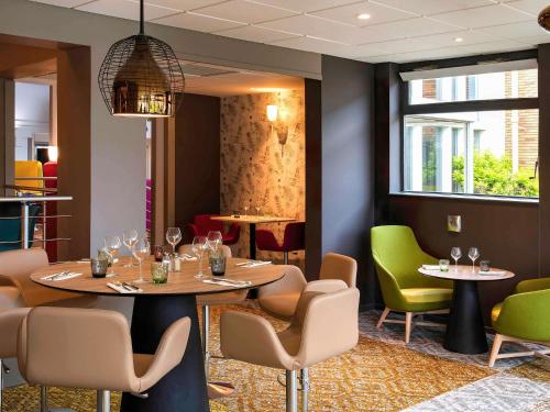 a dining room with two tables and chairs at Novotel Metz Amnéville in Maizières-lès-Metz
