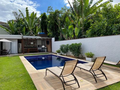 a backyard with a swimming pool and two chairs at Casa em Condomínio Maresias in São Sebastião