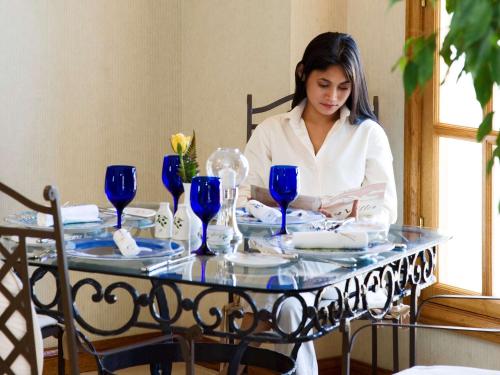 a woman sitting at a table with blue glasses at Treffen House Doha - Souq Waqif and next to Msheireb Metro Station in Doha
