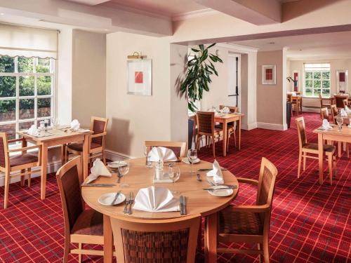 uma sala de jantar com mesas e cadeiras de madeira em Mercure Bolton Georgian House Hotel em Bolton