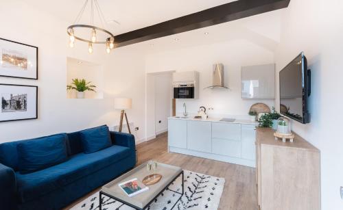 a living room with a blue couch and a kitchen at 14-16 Grosvenor Street Stylish Apartments - Chester in Chester