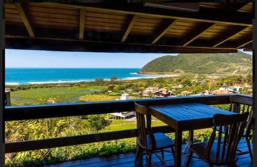 a table and two chairs on a balcony with the ocean at Morada Prainha in Garopaba