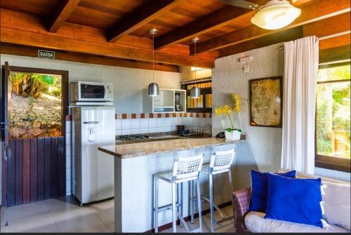 a kitchen with a counter and a bar with stools at Morada Prainha in Garopaba