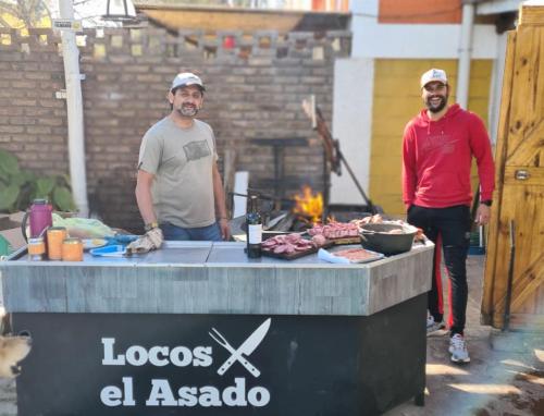 two men standing in front of a barbecue grill at Alojamiento Quincho Pascual in Las Compuertas