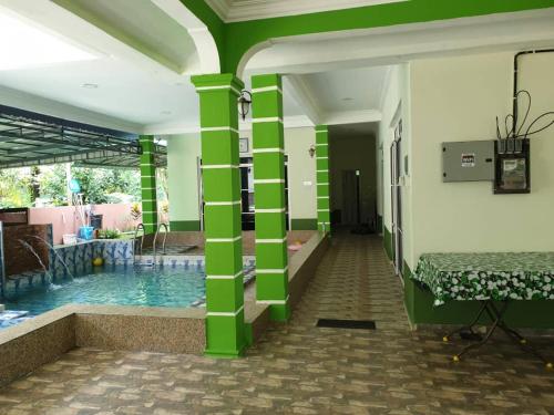 a room with a swimming pool and green columns at Inapdesa Teratak Bonda, Sepri REMBAU in Rembau