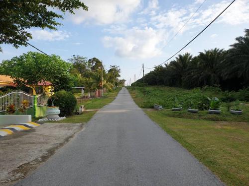 an empty road in a residential neighborhood with trees at Inapdesa Teratak Bonda, Sepri REMBAU in Rembau