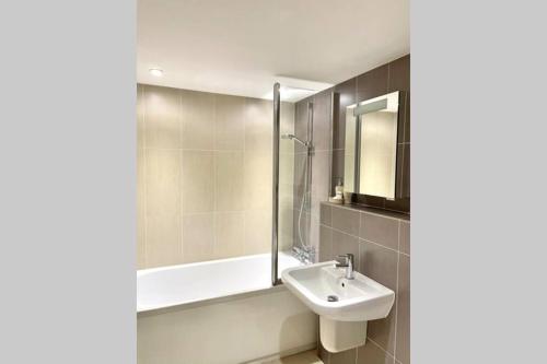 a bathroom with a sink and a bath tub at Luna Beach - Luxury Carbis Bay Apartment + Parking in Carbis Bay