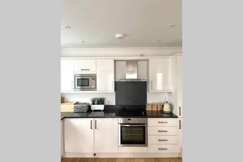 a kitchen with white cabinets and a stove top oven at Luna Beach - Luxury Carbis Bay Apartment + Parking in Carbis Bay