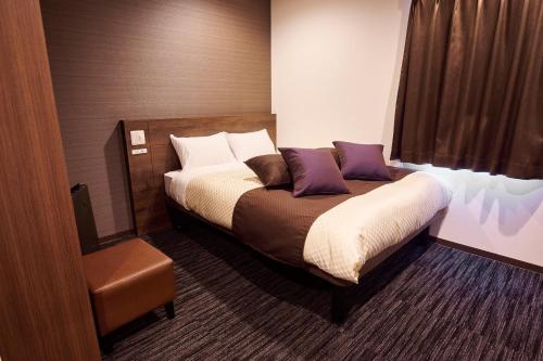 1 dormitorio con 1 cama con almohadas moradas y blancas en The CELECTON Abeno-Matsubara Ekimae, en Matsubara