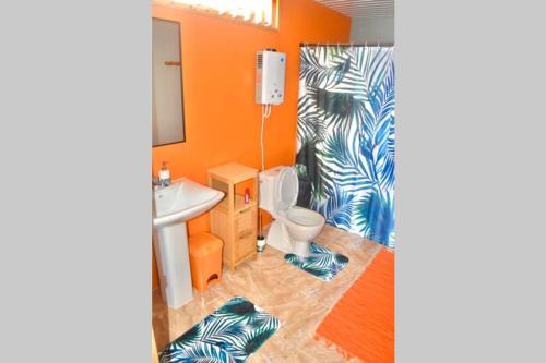 bagno con pareti arancioni, servizi igienici e lavandino di Hiti Tikehau, the ocean side bungalow a Tikehau
