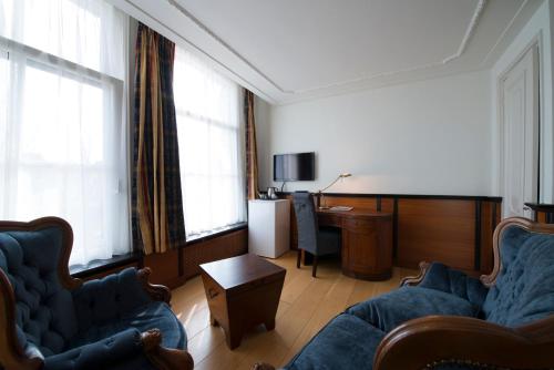 a living room with two blue chairs and a desk at Logement Garjen in Harlingen