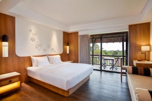 a bedroom with a large white bed and a balcony at Novotel Bogor Golf Resort in Bogor