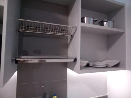 a kitchen with a shelf with plates and pans at Accommodation Rose Johannesburg in Johannesburg