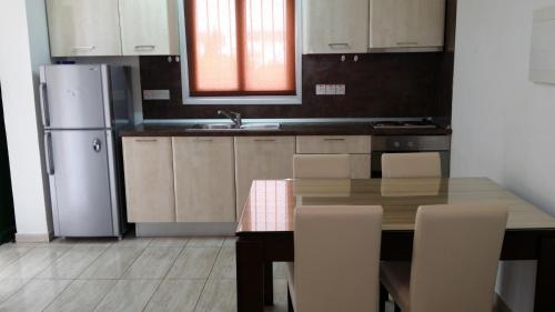 a kitchen with a wooden table and a refrigerator at Agrino Hotel Apartments in Ayia Napa
