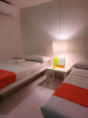 a room with two beds and a table with a lamp at Islands Stay Hotels Mactan in Mactan