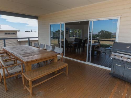 a patio with a wooden table and a grill on a deck at Shearers Rest 5 Davey Road in Normanville