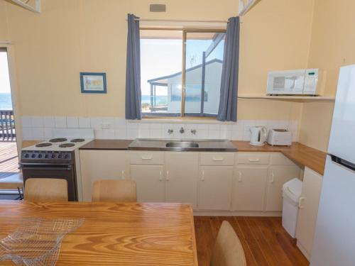 een keuken met een wastafel en een fornuis bij Sandy Feet 31 Gold Coast Drive in Normanville