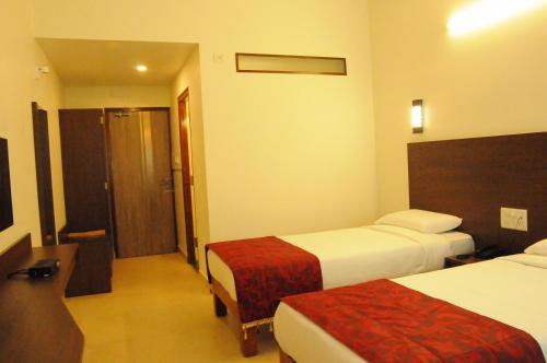 a hotel room with two beds and a bathroom at Palguni Residency in Hassan