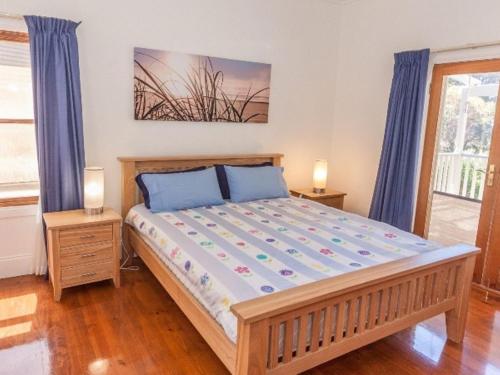 - une chambre avec un grand lit et des rideaux bleus dans l'établissement 3 Banksia Court, à Normanville