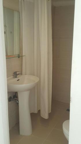 a bathroom with a sink and a white shower curtain at Islands Stay Hotels Mactan in Mactan