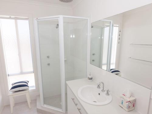 a white bathroom with a shower and a sink at 12 Lady Bay in Normanville