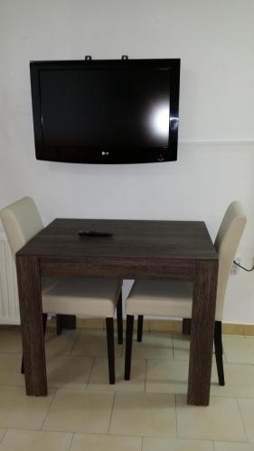 a wooden table with chairs and a television on a wall at Agrino Hotel Apartments in Ayia Napa