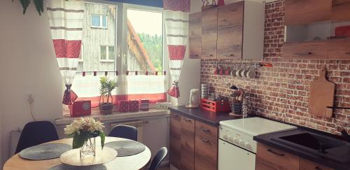 a kitchen with a table with a vase of flowers on it at Apartament Wrzos Bieszczady in Czarna