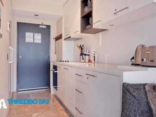 a kitchen with white counters and a blue door at The Peak 7 in Thredbo
