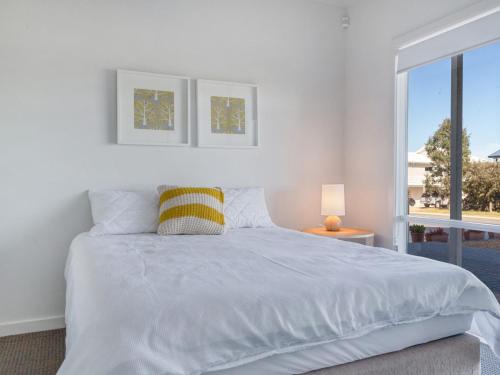 a white bedroom with a large bed and a window at Bungala Coastal Retreat 12 Nereus Drive in Normanville