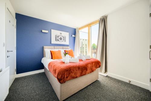 a bedroom with blue walls and a bed with orange sheets at Coventry Luxury Townhouse City Centre Private Parking Sleeps 9 by EMPOWER HOMES in Coventry