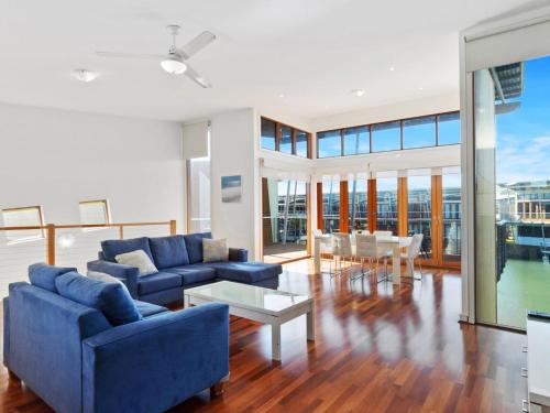 a living room with blue couches and a table at Large Villa, overlooking lagoon close to the pool. in Normanville