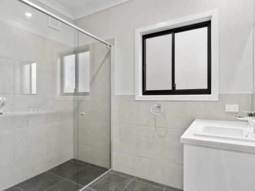 a bathroom with a glass shower and a sink at 8 Huntingdale Drive in Normanville