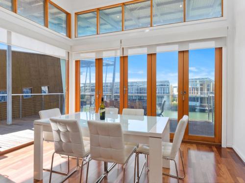 a dining room with a white table and white chairs at Large Villa, overlooking lagoon close to the pool. in Normanville
