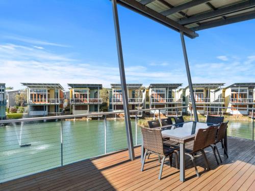 a balcony with a table and chairs and a view of the water at Large Villa, overlooking lagoon close to the pool. in Normanville