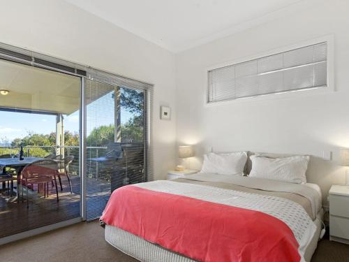 a bedroom with a bed and a balcony with a table at Yellow Door on Stacey 17 Stacey Drive in Carrickalinga