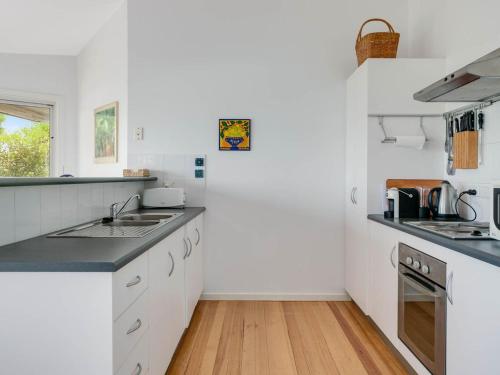 a kitchen with white cabinets and a wooden floor at Seven on Scenic - 7 Scenic View Drive, Second Valley in Second Valley