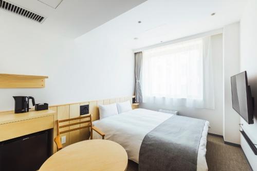 a hotel room with a bed and a tv at Hotel Nupka in Obihiro