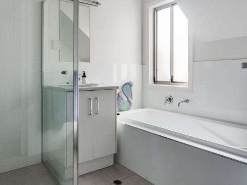 a white bathroom with a tub and a sink at 52 Turnberry Drive in Normanville