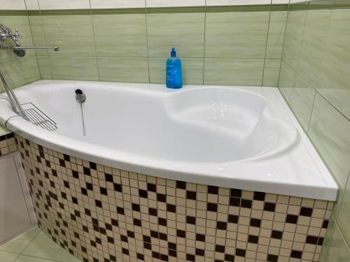 a white bath tub with a blue bottle on it at V15 Apartment in Druskininkai