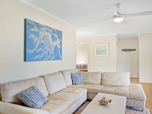 a living room with a white couch and a blue painting at Carried Away 9 Dorset Court in Carrickalinga