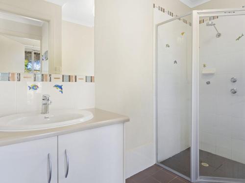a white bathroom with a sink and a shower at Carried Away 9 Dorset Court in Carrickalinga
