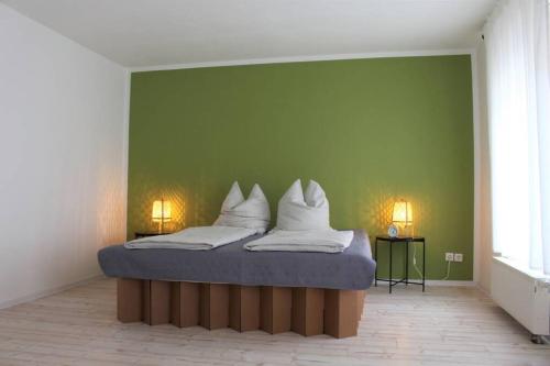 Bett in einem Zimmer mit grüner Wand in der Unterkunft FeWo Zum Schloss in Weißenfels