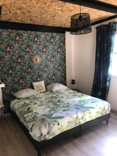 1 dormitorio con 1 cama y papel pintado con motivos florales en La Villa Citronnier, en Petite Île